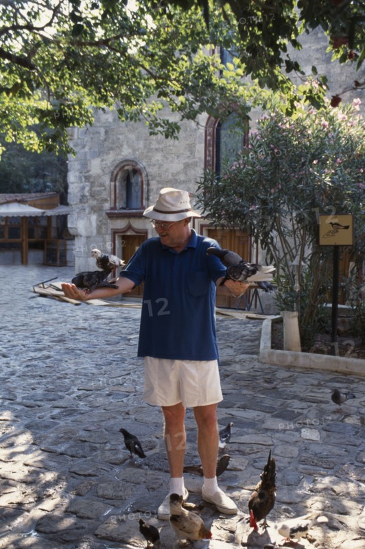 TURKEY, Bodrum, Dr George Bass founder of Nautical Archaeology Institute with his arms stretched out holding pigeons
