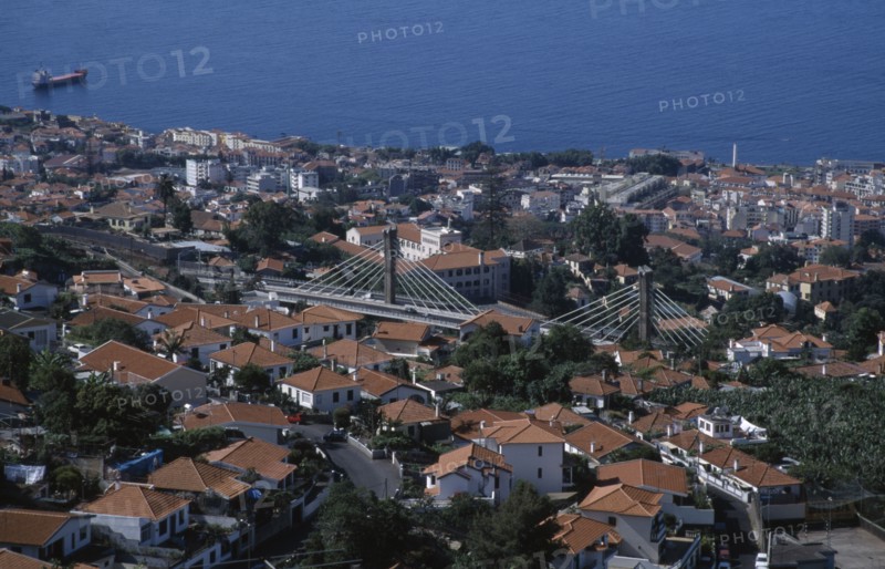 PORTUGAL, Madeira, Funchal, Elevated view over roof tops with the Motorway flyover leading to the airport amongst buildings running through the city