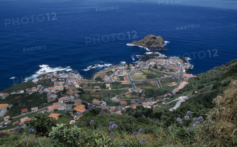 PORTUGAL, Madeira, Elevated view from the north coastal road over Porto do Moniz rooftops and coastline