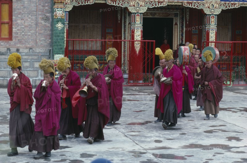 CHINA, Qinghai Province, Quezhang Lamasery, "Tibetan Yellow Hat Buddhists playing horns, drums and cymbals during ceremony."