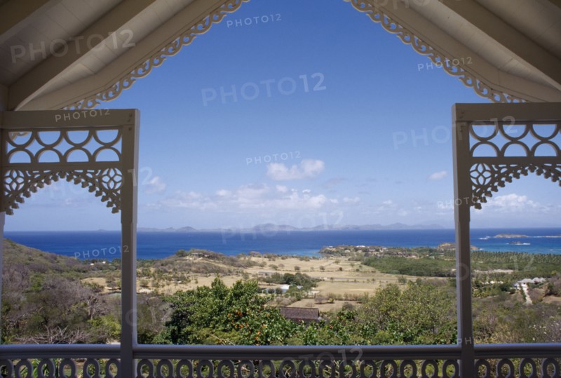 GRENADINES, Mustique, View from a carved Villa balcony over land and trees towards the coastline
