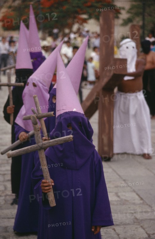 MEXICO, Oaxaca, "Young, masked penitents carrying wooden crosses during Easter parade. "