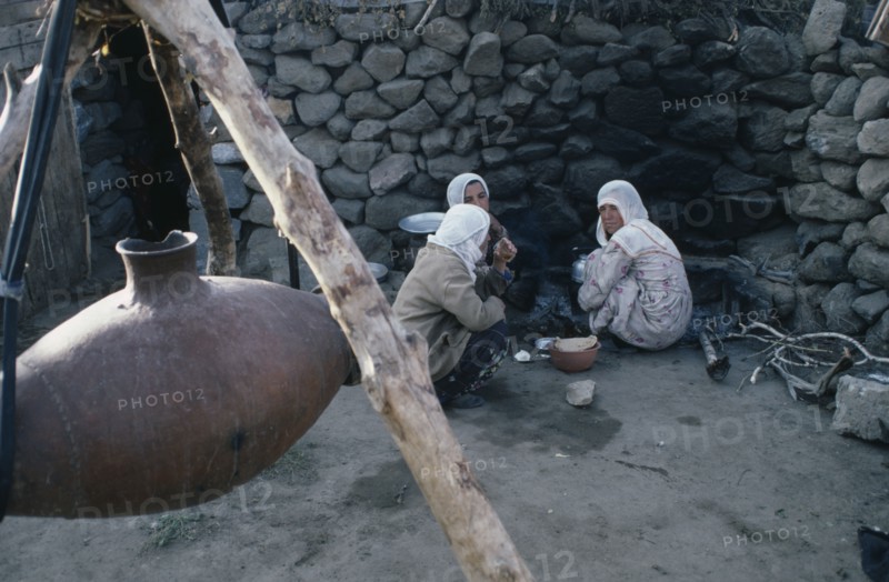 TURKEY, East, Nemrut, Women sitting on ground beside suspended vessel used to churn milk.