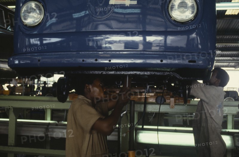 NIGERIA, Lagos, Men working on underside of car on Volkswagen car assembly line.