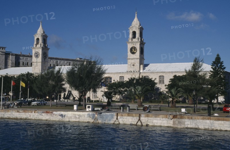 BERMUDA, Sandys Parish, Clocktower Mall formally the offices of the Royal Naval Dockyard seen from across water with trees along the banks