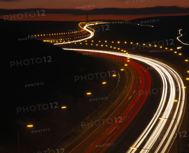 TRANSPORT, Traffic, Motorway, M62 Motorway. Elevated view over traffic in motion blur with light trails seen in late evening with a red sky