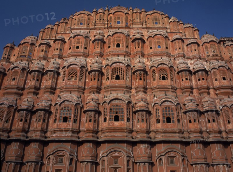 INDIA, Rajasthan, Jaipur, "Hawa Mahal. Exterior of pyramid shaped structure made of sandstone which has tier after tier of small casements each with tiny lattice worked pink windows, small balconies and arched roofs with hanging cornices"