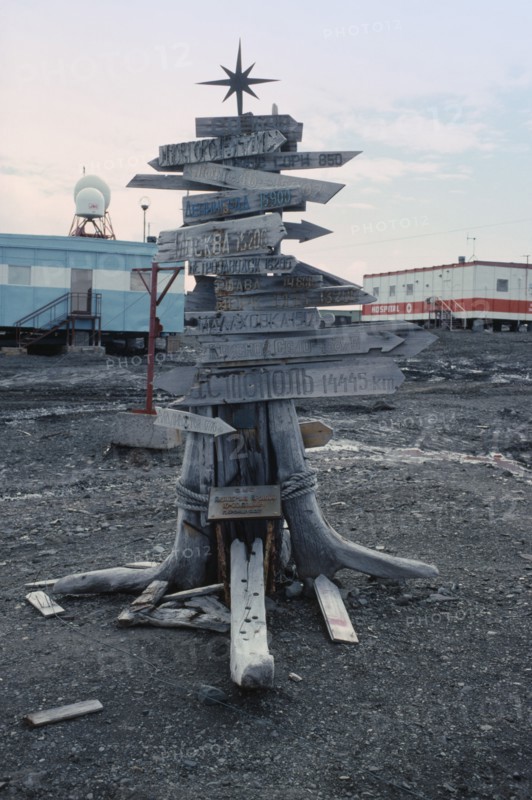 ANTARCTICA, King George Island, Russian Bellingshausen Station. Wooden sign post with star on top with arrows pointing to the distance home to Russia