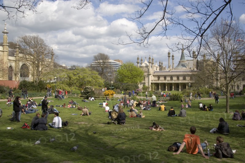 ENGLAND, East Sussex, Brighton, The Royal Pavilion gardens with people relaxing in the spring sunshine.