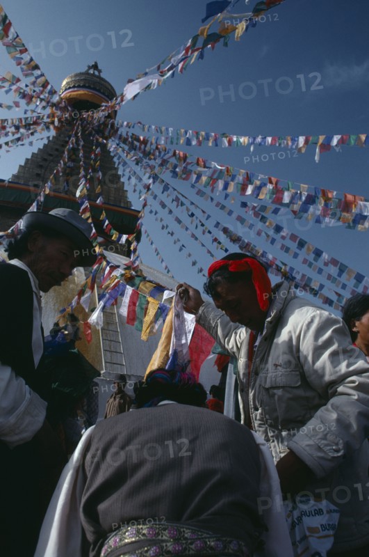 NEPAL, Kathmandu, Bodhanth Stupa, Tibetans hanging stupa with prayer flags during new year celebrations.