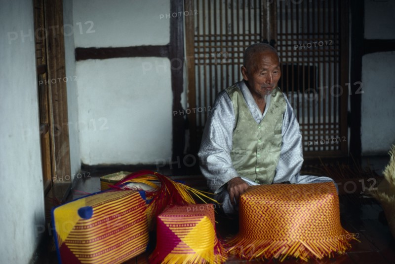 SOUTH KOREA, People, Men, Portrait of Kim Tong Yon a master bamboo craftsman who has been declared a Living National Treasure by the government. Seated indoor with examples of his colourful  baskets