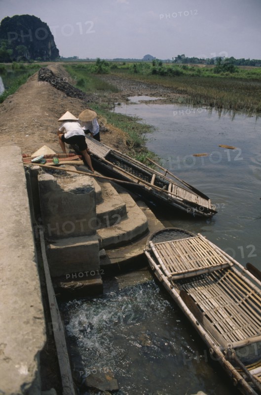 VIETNAM, Hoa Binh Province, Hoa Lu, People moving boat over dyke