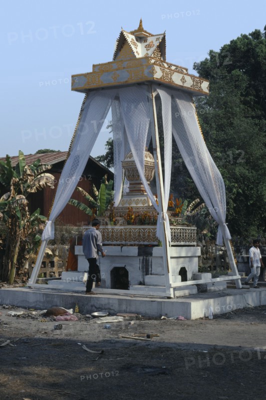 LAOS, Vientiane, Man about to light funeral pyre at a cremation