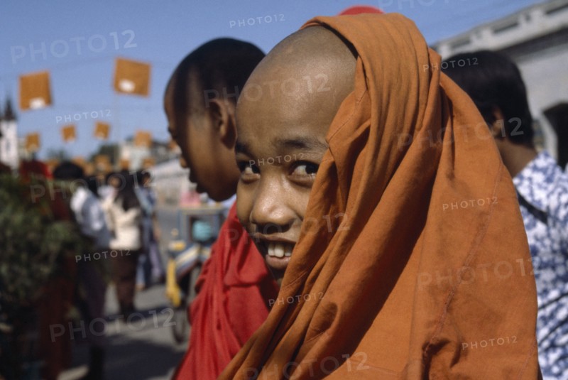MYANMAR, Mandalay, Young Buddhist monk smiling wearing orange robes