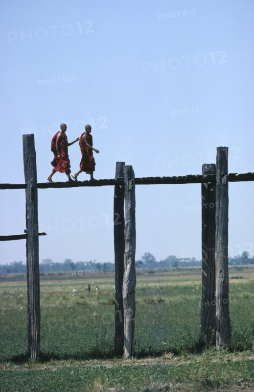 MYANMAR,  Mandalay, Monks walking aross the wooden Amarapura Bridge over the flood plain
