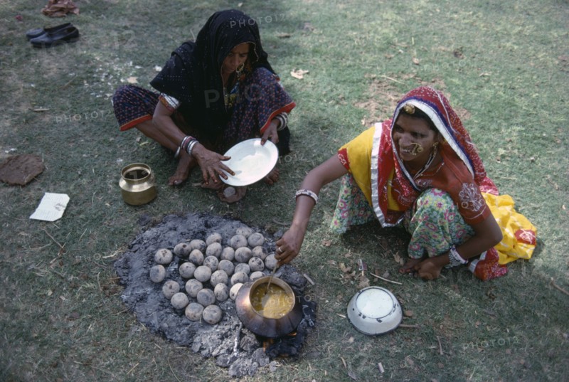 INDIA, Rajasthan, Pushkar, Women cooking over small open fire and hot ashes on the ground.