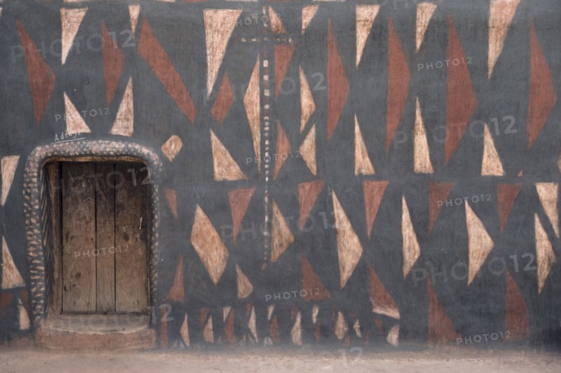 GHANA, North, Architecture, "Traditional mud architecture.  Walls painted with broken calabash pattern in red, black and white, an expression of ever useful.  Raised doorway keeps out water."