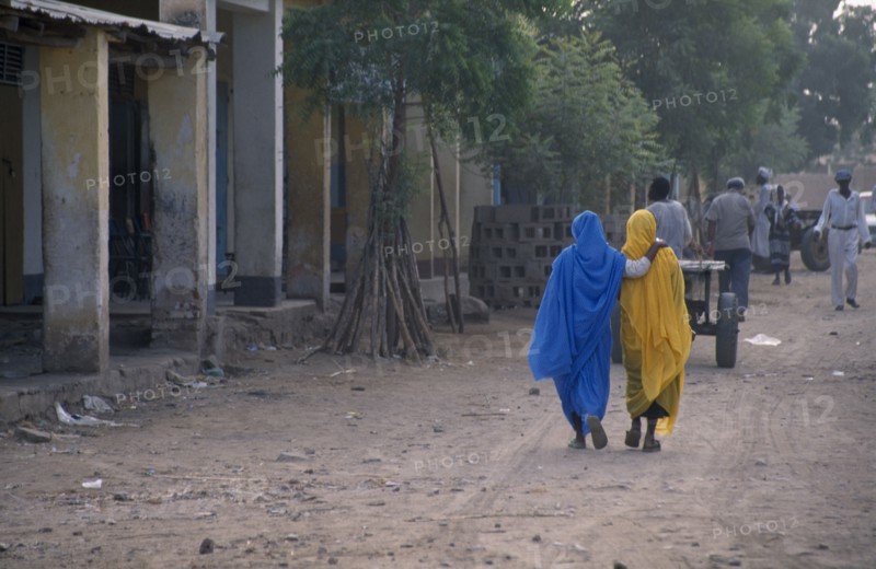 ERITREA, Tessanie, Two women with one woman resting her hand on others shoulder walking along road wearing colourful muslim clothing