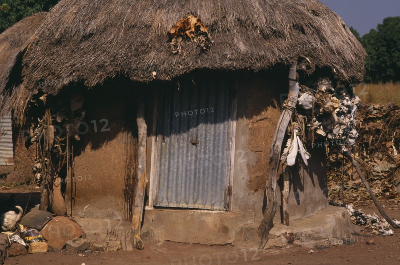 IVORY COAST, Architecture, Village hut with straw roof and fetishes attached to exterior