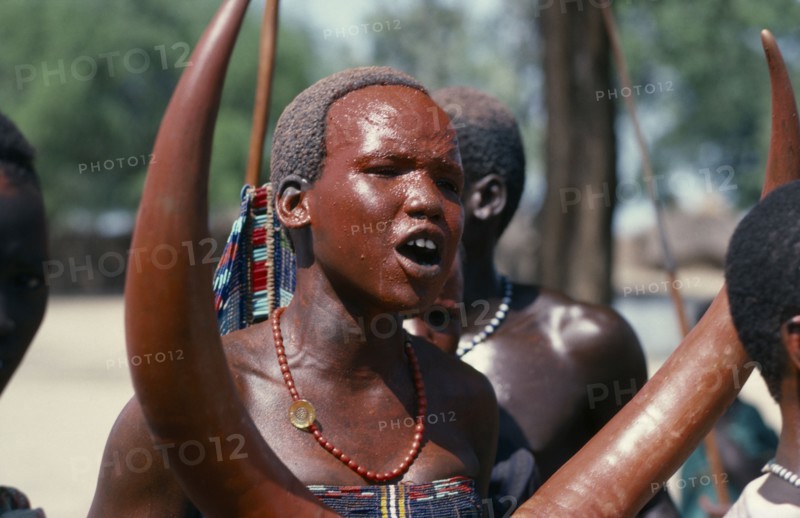 SUDAN, Tribal People, Dinka girl with red painted face at festival celebrating the return of cattle herds to the Toich or pastureland from swamps.