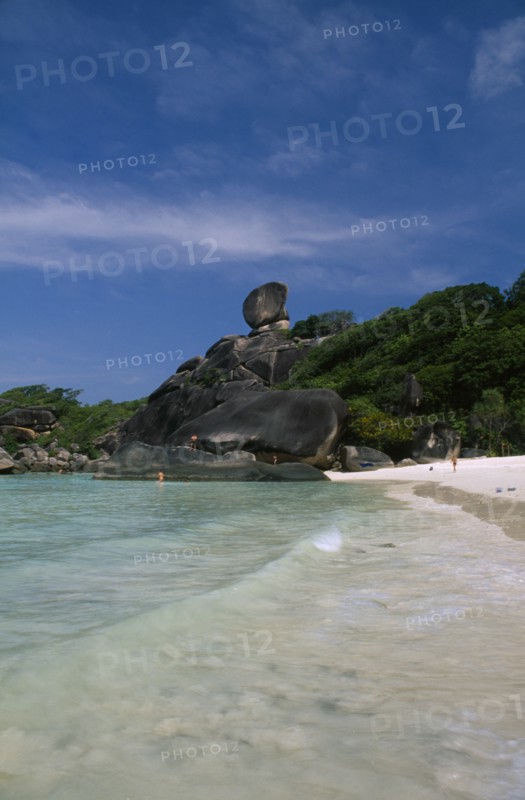 THAILAND, Koh Similan  , Sail Rock, View from the water’s edge of people on the sandy beach and climbing on the rocky coast line.