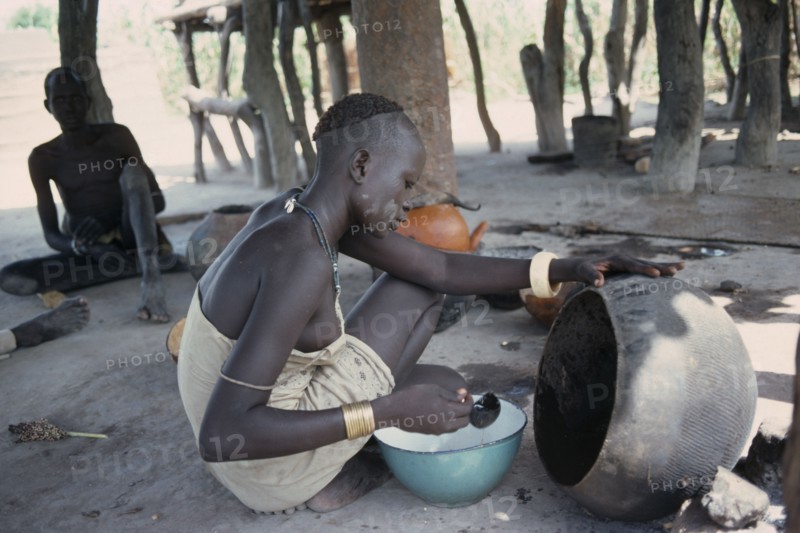 SUDAN, Tribal People, Dinka woman cooking with oil from shea butter fruit.