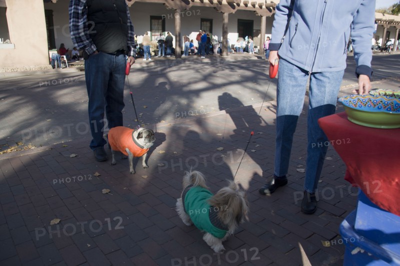 USA, New Mexico, Santa Fe, Two people out walking dogs on leads and standing beside a crafts stall in the Plaza opposite the Governors Palace