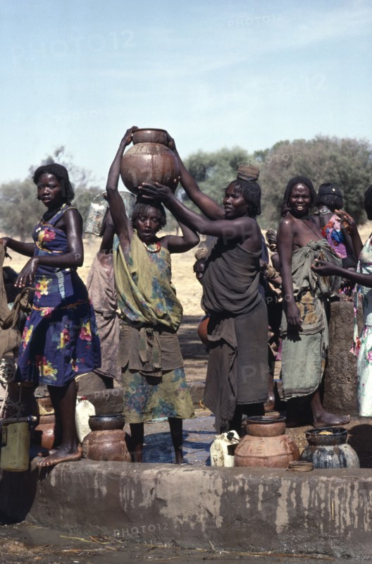 SUDAN, Habila Settlement, Group of Chadian refugee women collecting water from well.
