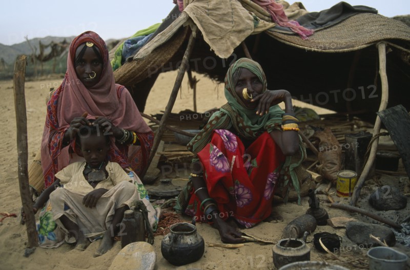 SUDAN, North East, Gadem Gafriet Camp, Beja nomad Beni Amer tribeswomen and child outside tent in refugee settlement.