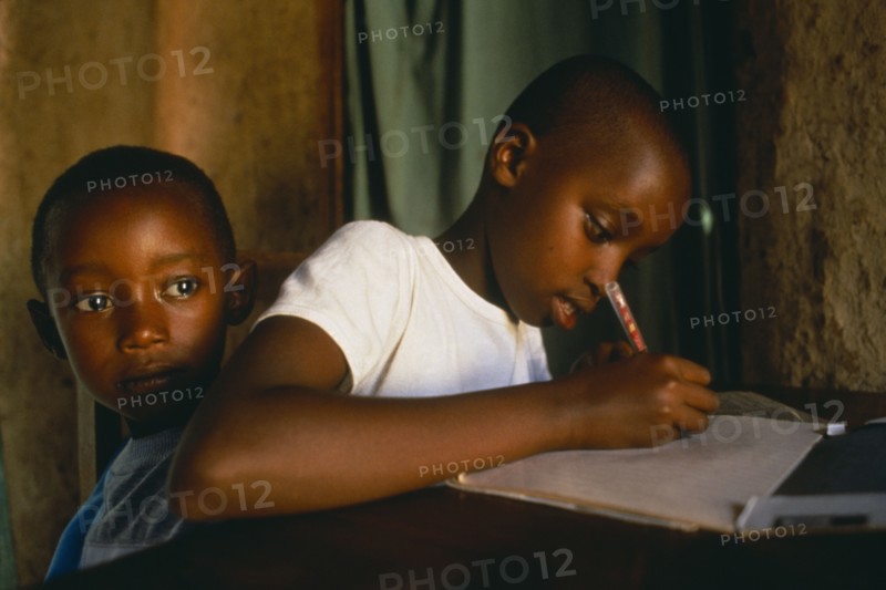 RWANDA, Akagera, "Children of Tutsi returnee family doing homework.  The family fled to Uganda over thirty years ago, but have returned under the new regime."