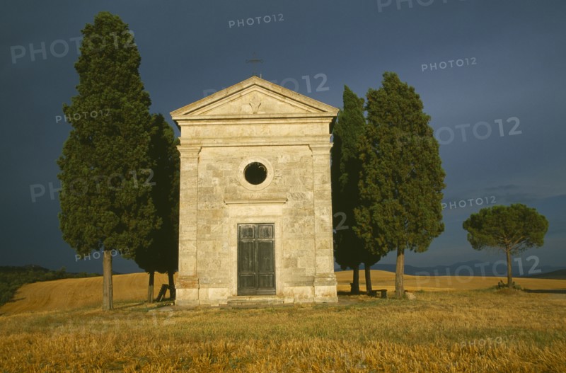 ITALY, Tuscany, Small stone chapel and cyrpress trees near San Quirico d’Orcia.