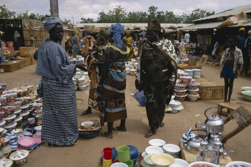NIGER, Sahel, Niamey, Busy market scene with group of women looking at cooking utensils and pots in the foreground.