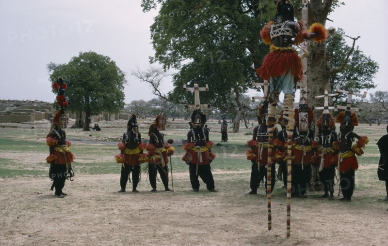 MALI, Ceremony, Dogon masked stilt dancer with others on ground below.