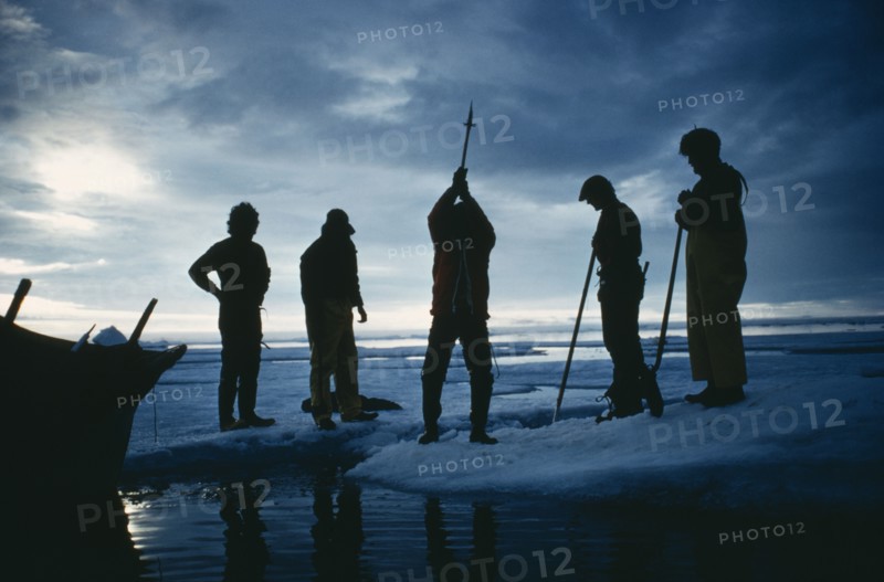 ARCTIC, Eskimos, "Silhouette of a man using an axe to cut through ice. Others stand round, two holding spears."