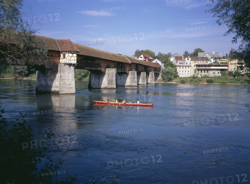 GERMANY, Baden Wurttemberg, Covered wooden bridge over the Rhine which links Badsackingen with the Stein in Switzerland. People in row boat.