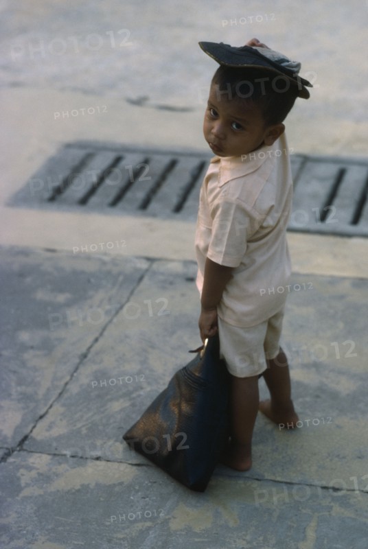 MYANMAR, Yangon, Portrait of young child standing on pavement.