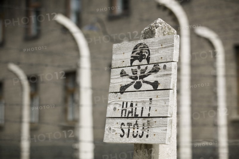 POLAND, Oswiecim, Auschwitz, Detail of a sign in the concentration camp. Black scull and crossbones on white painted wood with a warning written underneath.
