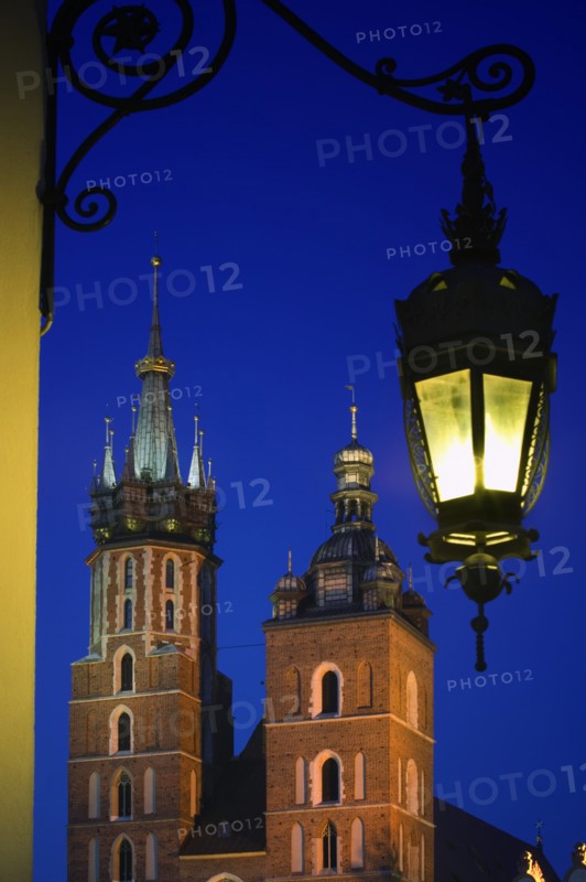 POLAND, Krakow, "Detail of St Mary's Church in Rynek Glowny, Night time with lit lamp with decorative bracket on wall."