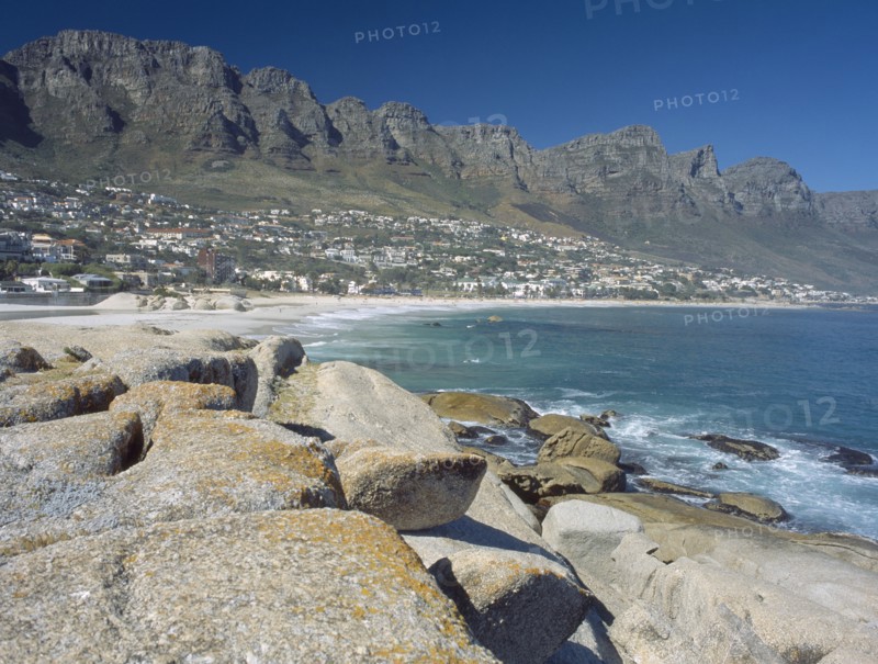 SOUTH AFRICA, Western Cape, Cape Penninsula, View across rocks towards Clifton bay and beach.  Hillside buildings with the Twelve Apostles behind