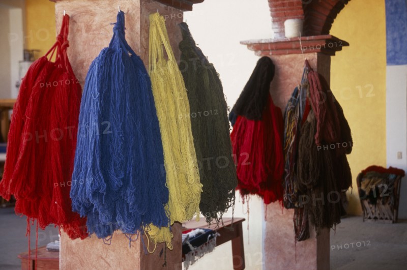 MEXICO, Oaxaca, Teotitlan del Valle. Different coloured thread handing on pillars in the weaving centre.