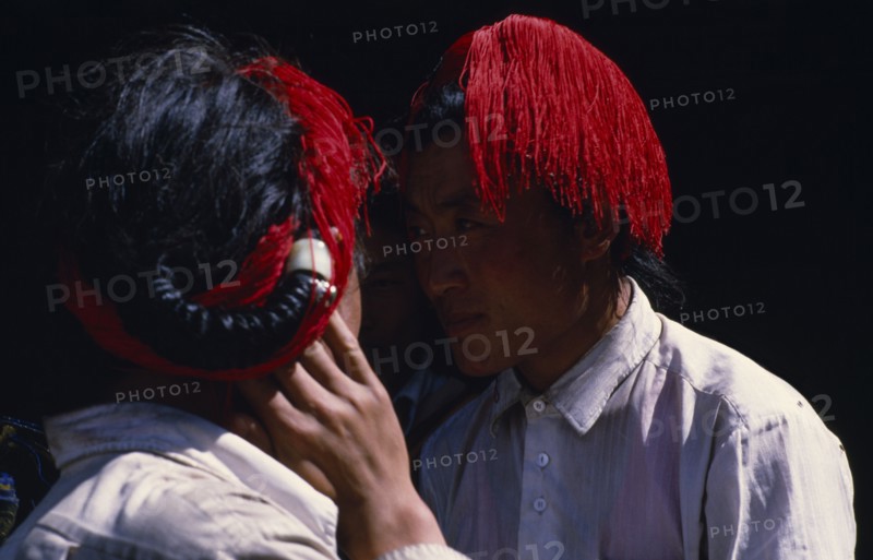 TIBET, People, Men, Head and shoulders shot of two Khampa men with hair worn in long braids intertwined with red string.