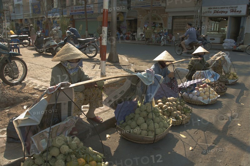 VIETNAM, South, Ho Chi Minh City, Fruit sellers wearing conical hats on the street in the centre of town