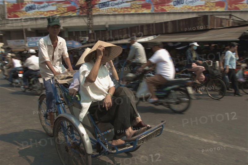 VIETNAM, South, Ho Chi Minh City, Two women riding a Cyclo on a busy street