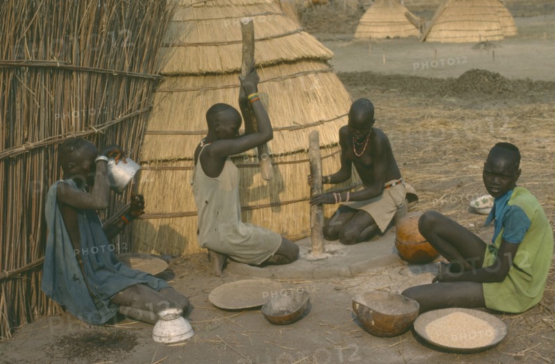 SUDAN, Agriculture, Dinka women pounding millet outside their hut.