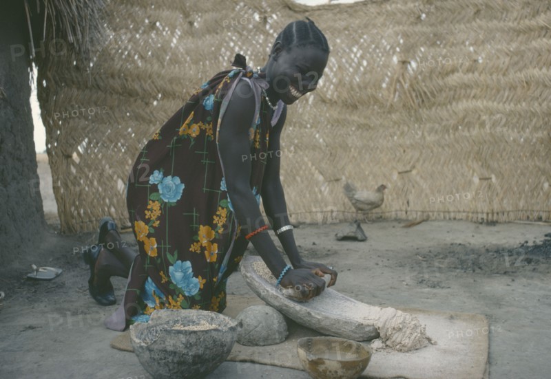 SUDAN, People, Shilluk woman grinding sorghum to make bread.