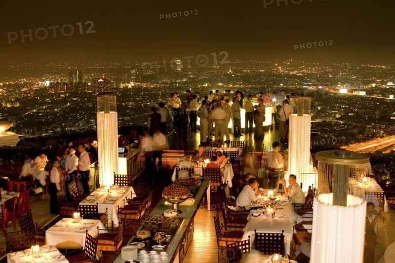 THAILAND, Bangkok, Sorocco Restaurant. People dining at tables with the Bangkok Skyline in the background.