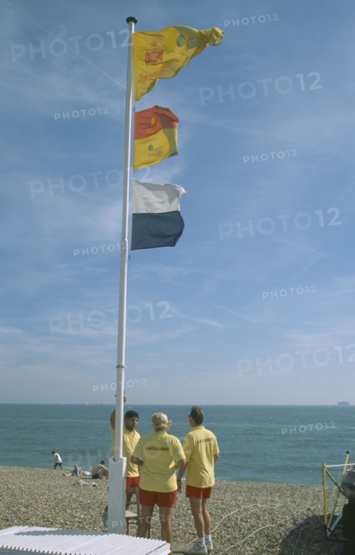 ENGLAND, Hampshire, Portsmouth, Lifeguards on beach under flag pole.