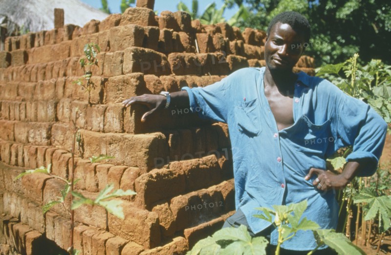 MALAWI, Mulanje, Portrait of man standing next  to brick building in a Ekhamuru Village.