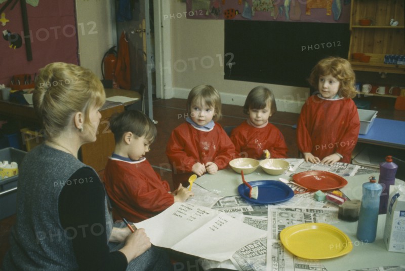 EDUCATION, School, Nursery, Nursery School children with teacher gathered around table taking part in art class.