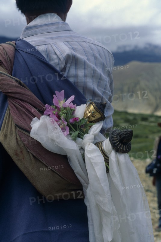 NEPAL, Mustang, Buddha figure wrapped in ceremonial scarves being carried through the summer fields during Lok Khor festival to bring good harvests and protection.